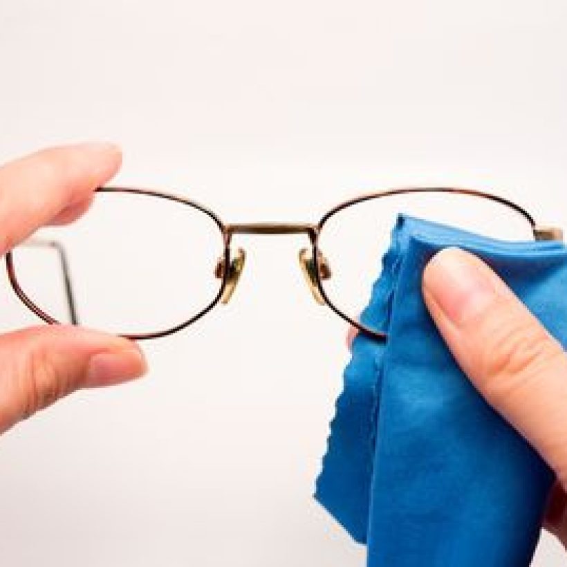 woman cleaning his glasses with blue cloth woman cleaning his glasses with blue cloth